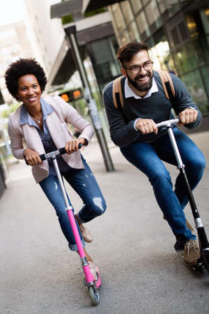 Two smiling business people driving electric scooter going to work.の写真素材
