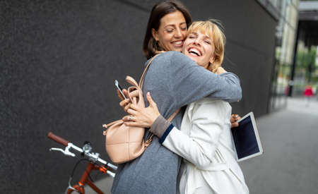 Happy meeting of two women friends hugging in the streetの写真素材