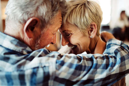 Happy romantic senior couple hugging and enjoying retirement at homeの写真素材