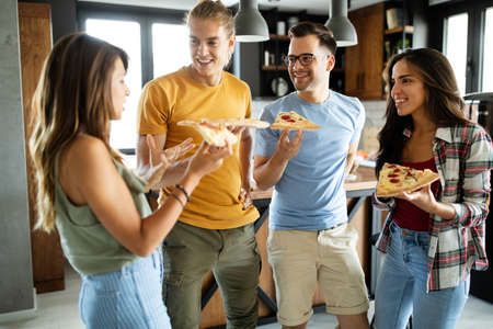 Group of friends are having party at home, eating pizza and having fun.の写真素材