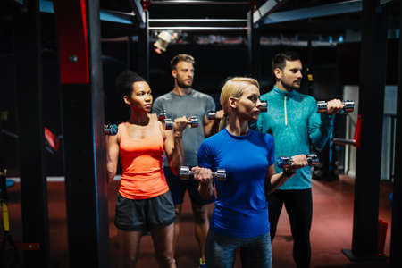 Attractive sports people friends are working out in gym