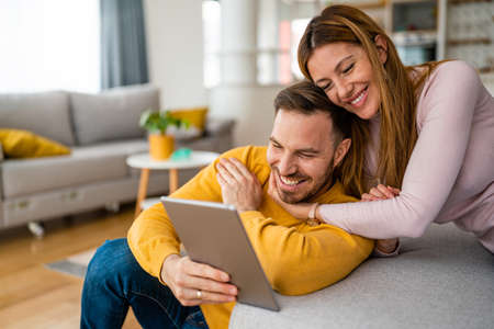 Happy cheerful couple in love using digital tablet at homeの写真素材