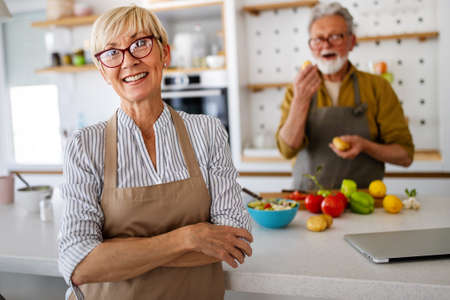 Senior couple having fun, cooking together in home kitchenの写真素材