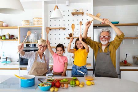 Happy senior couple having breakfast with their grandchildren at homeの写真素材