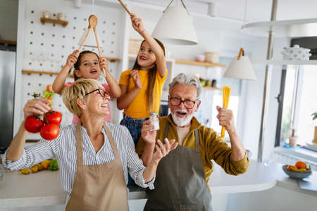Happy senior couple having breakfast with their grandchildren at homeの写真素材