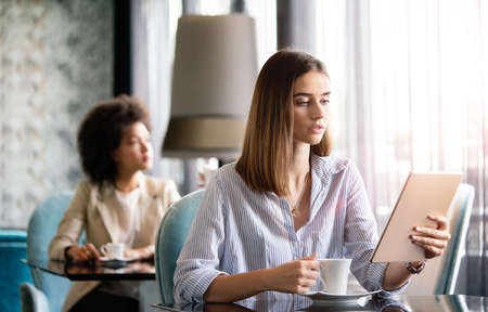 Attractive businesswoman using a digital tablet while sitting in cafeの写真素材