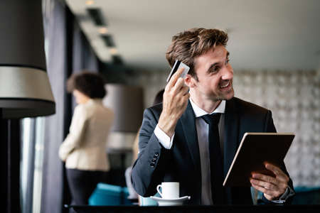 Portrait of cheerful businessman paying for order with credit card in cafeの写真素材