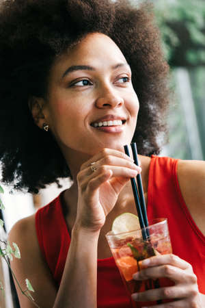 Beautiful happy black woman drinking healthy drink and smiling