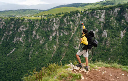 Hiker with backpacks reaches the summit of mountain peak. Success, freedom and happiness conceptの写真素材