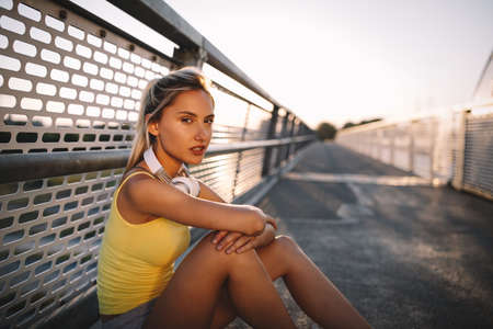 Portrait of fit cheerful blonde woman resting after a run in a cityの写真素材
