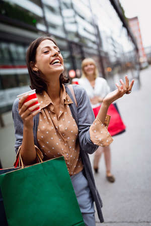 Beautiful happy women with shopping bags walking and having funの写真素材