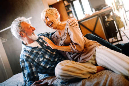 Happy smiling senior couple embracing together at homeの写真素材