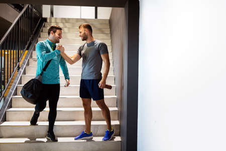Sport, fitness, friends, lifestyle concept. Smiling men friends talking after workout in gym