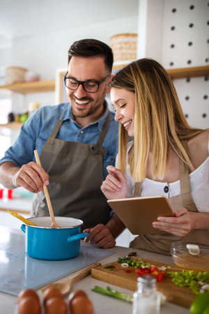 Happy young couple enjoys and having fun preparing healthy meal together at home kitchen.の写真素材