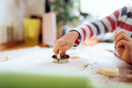 Happy boy preparing a scone in the kitchenの写真素材