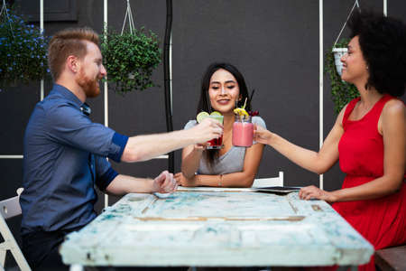 Diverse group of happy friends having fun, talking in cafe outdoor at summerの写真素材