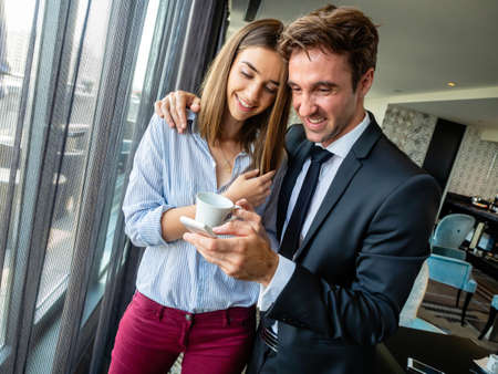 Happy young couple using mobile phone, having a great time togetherの写真素材
