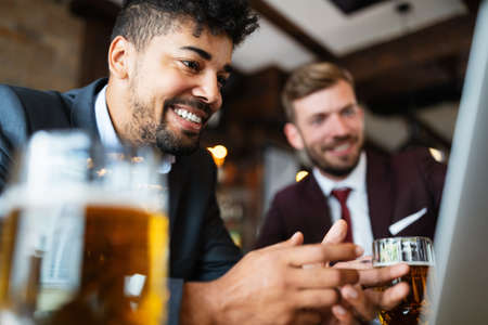 Happy young businessmen in suits are smiling and talking in a restaurantの写真素材