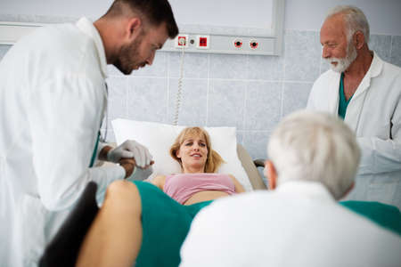 Obstetricians assisting in the hospital woman in labor pushes to give birthの写真素材