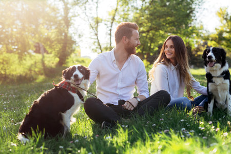 Happy couple in love playing with dogs in the park