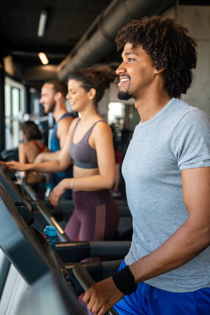 Group of young people running on treadmills in sport gymの写真素材