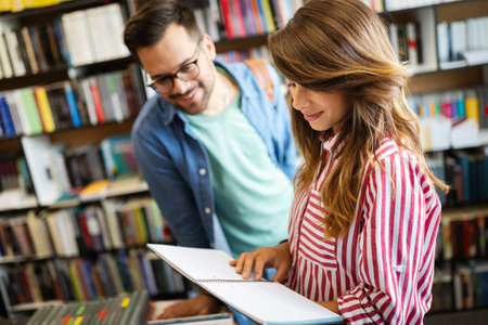 Group of happy students reading books and preparing to exam in libraryの写真素材