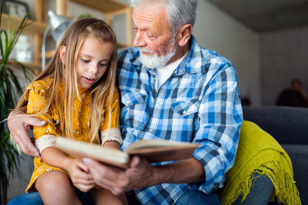 Bearded grandfather and his grandchild are having fun reading a book togetherの写真素材