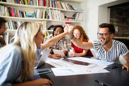 Group of successful happy business people in office celebrating profits