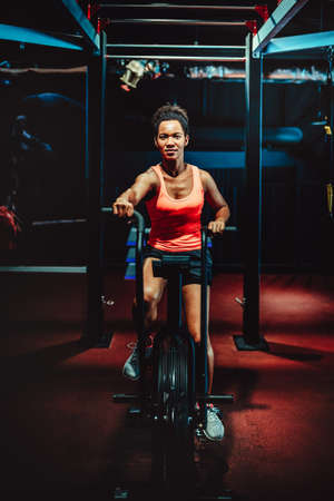 Beautiful fit woman training by riding a bicycle in a gymの写真素材