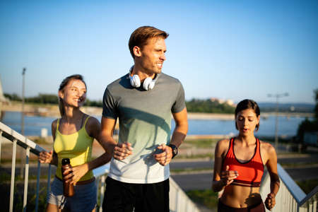 Fit happy friends jogging and running together outdoor in city