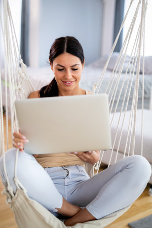 Beautiful young woman working on her laptop at homeの写真素材