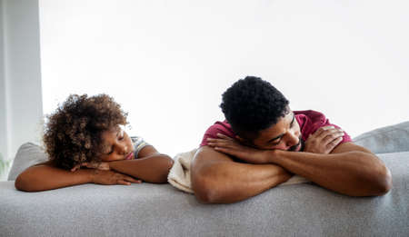 Tired parent father with his child trying to take a nap at home. Stay at home dad.の写真素材