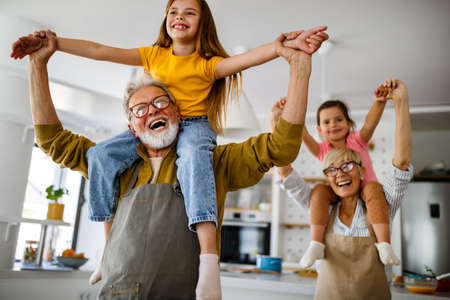 Happy grandparents having fun times with children at homeの写真素材