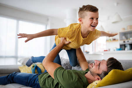 Cheerful young boy having fun with father together at homeの写真素材
