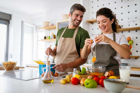 Happy young couple have fun in modern kitchen while preparing fresh foodの写真素材