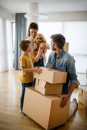Happy family with children moving with boxes in a new apartment house.の写真素材