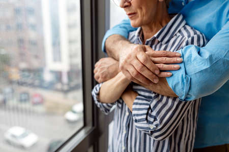 Happy senior couple in love hugging and bonding with true emotions at homeの写真素材
