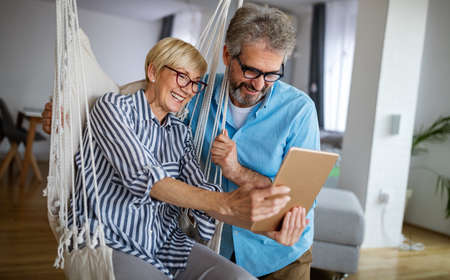 Happy smiling mature couple using digital tablet at homeの写真素材
