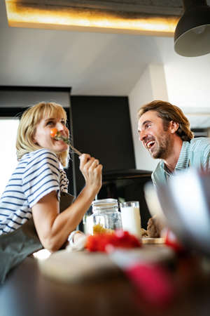 Happy couple cooking healthy food and having fun together in their kitchenの写真素材