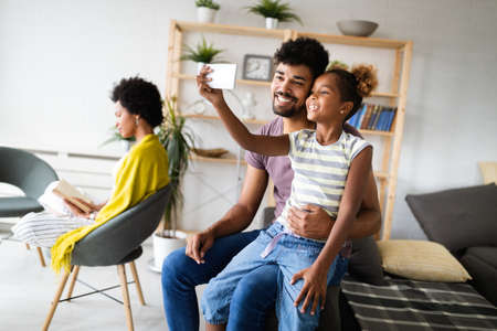 Happy family, technology concept. Father spending time with his daughter, using mobile phone.の写真素材