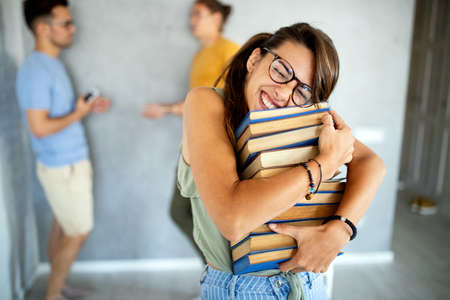 Enjoying university life. Beautiful happy woman holding books and smiling. Education conceptの写真素材