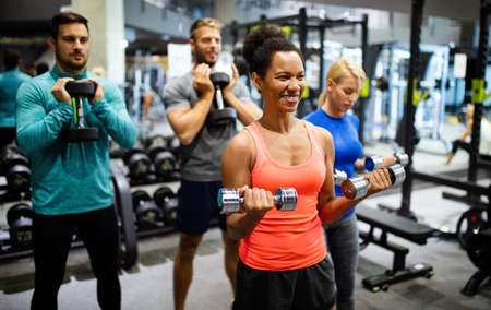 Group of young happy fit people doing exercises in gymの写真素材