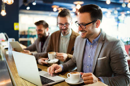 Happy business people talking and laughing together at cafeの写真素材
