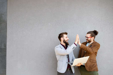 Positive successful business specialists discussing plan with laptop outdoors.の写真素材