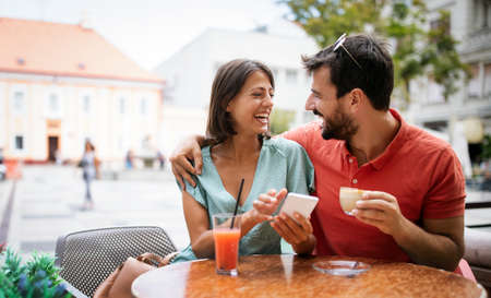Happy couple drinking coffee in outdoors cafe on summer vacation