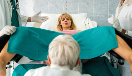 Woman giving birth in hospital with medical doctor teamの写真素材