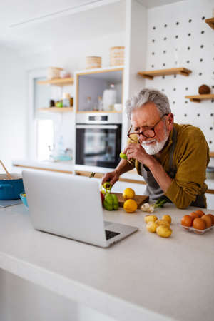 Happy retired senior man cooking in kitchen. Retirement, hobby people conceptの写真素材