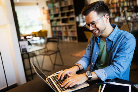 Smiling male student working and studying in a library