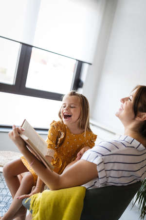 Girl and her pregnant mother reading book together. Family time
