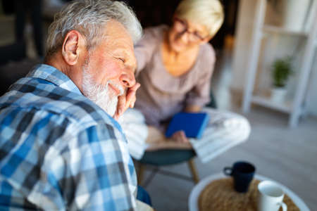 Mature couple relaxing at home and reading book togetherの写真素材